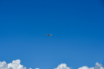 青空を滑空するオレンジ旅客機