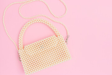 Handmade bag made from pearl imitation beads on a pink background. Elegance diy design accessory.