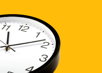 A white circular black alarm clock on a bright yellow background wall in pastel colors. minimal...