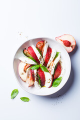 Caprese salad with peach, basil and mozzarella, white background.