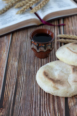 Bread and wine with open holy bible book and ripe wheat in the background. Close-up. Christian biblical concept of spiritual food and drink.