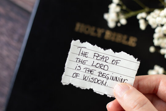 Fear of the LORD is the beginning of wisdom, handwritten Christian quote and holy bible book. Close-up. Christian blessing, reverence, love, and obedience to God Jesus Christ, biblical concept.