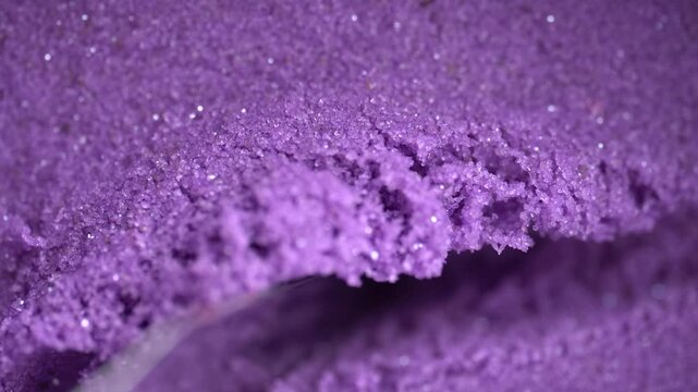 Metal spatula touching the purple kinetic sand. Textured, crumbly kinetic sand in lavender color. Kinetic sand background