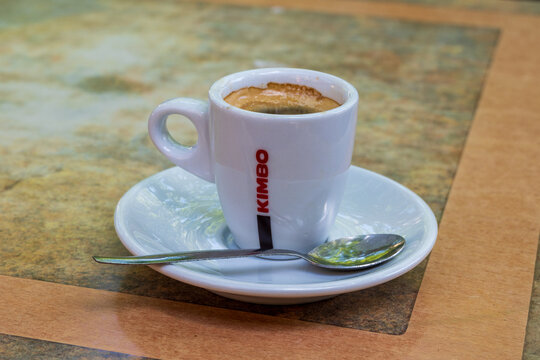 A classic KImbo brand cup of espresso coffee served in a small cup with saucer and spoon