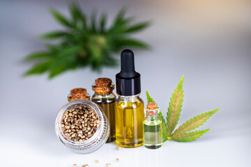 Hemp oil and cannabis leaves on light background