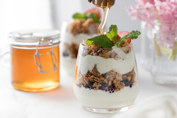Yogurt with crispy granola, berries and honey for a delicious breakfast. Healthy eating.