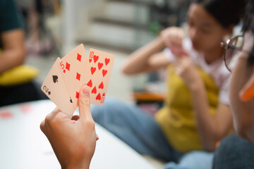 Diverse people playing a card game in the living room, Asian family playing games together