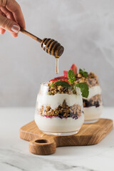 Yogurt with crispy granola, berries and honey for a delicious breakfast. Healthy eating.