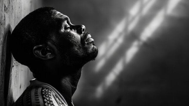 Black Prison. Afro-American Male Praying and Seeking Light and Justice with Profound Belief