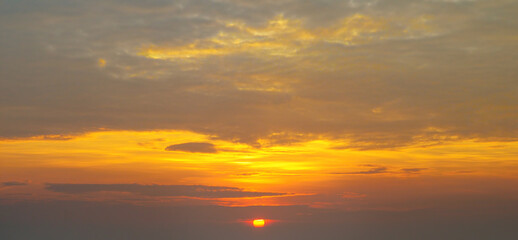 The morning sky looked like a bright golden sky. The sunrise is decorated with clouds in various shapes. Wide photo.
