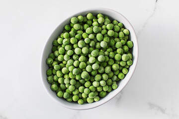 A bowl of frozen green peas on a white background. Fresh and healthy vegetable