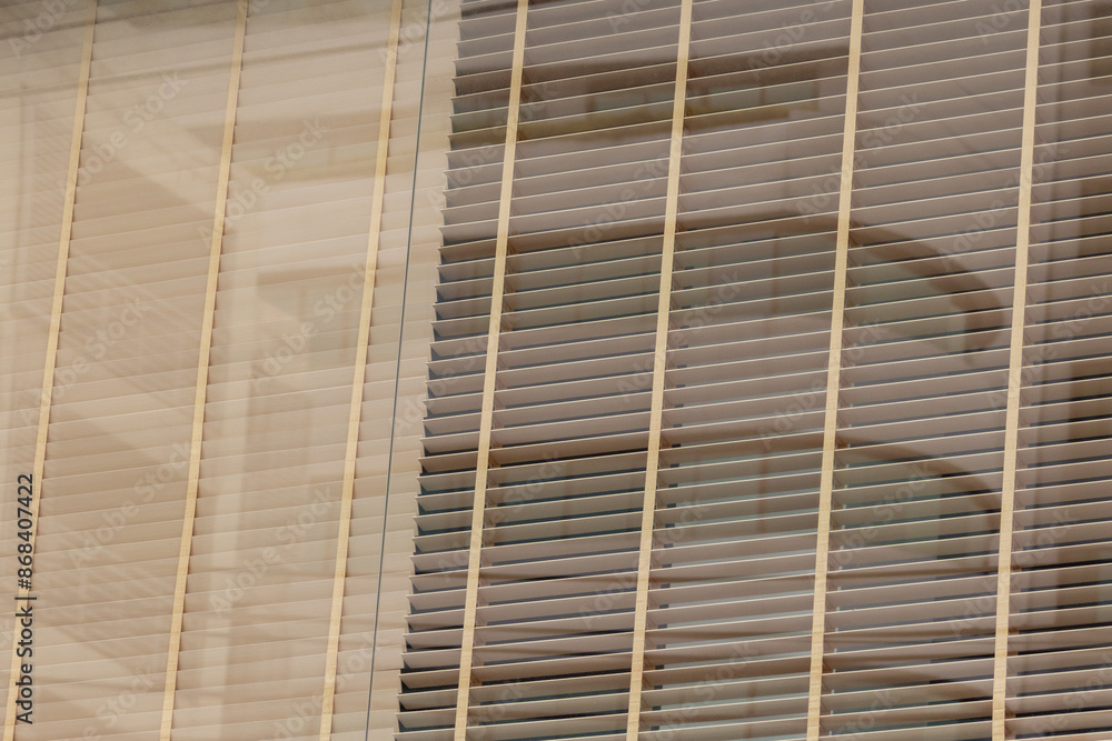 Wall mural a window with wooden blinds and a reflection of a building in the background