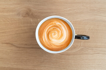 Top view on delicious cappuccino in ceramic cup standing on the wooden table