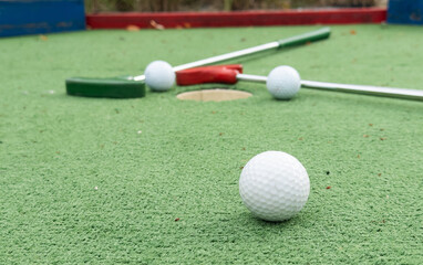 Fun vacation entertainment for summertime. Playing mini golf on green grass outdoors. Setting goals and winning lifestyle concept. Competition at golf course: two crossed sticks. Blank space for copy.