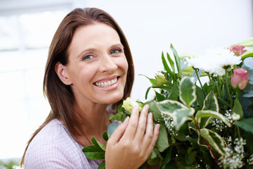 Smile, portrait and woman with flowers for present, bouquet and happiness with anniversary gift. Floral, plants and mature lady with decoration, fragrance and arrangement at home or house with smell