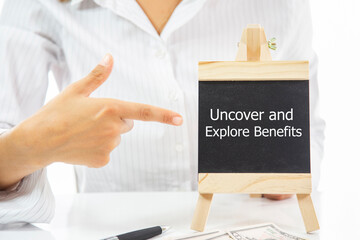 A woman pointing at a blackboard with the word Uncover and Explore Benefits written on it