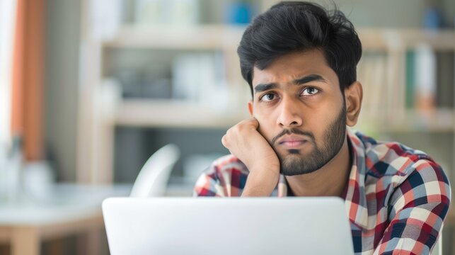 Confused Office. Young Indian Businessman Contemplating Problem Solution with Laptop at Home Workspace