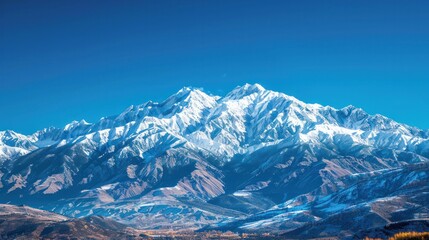 Fototapeta premium A snow-covered mountain range under a clear blue sky, capturing the majesty of nature