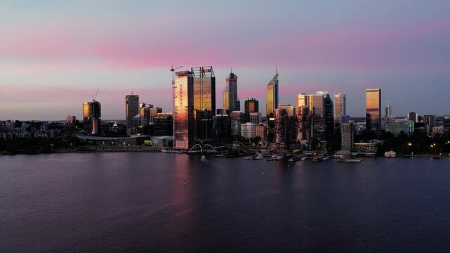A beautiful aerial view of the Perth skyline at sunset, featuring pink clouds and the Swan River.