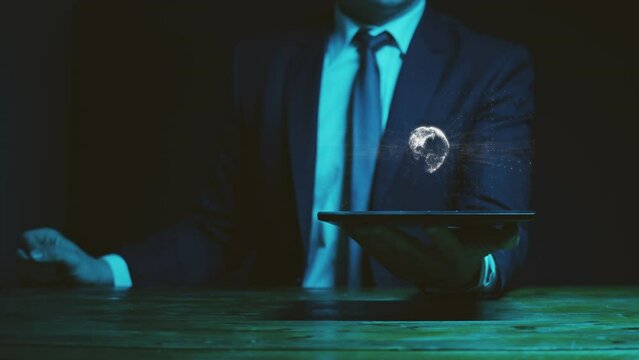 A businessman in a suit holds a graphics tablet above which there is a hologram with a rotating model of the globe towards which the information noise of the universe tends. Concept of research. Cg