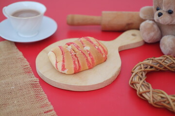 Strawberry bread with tea and teddy bear on red background
