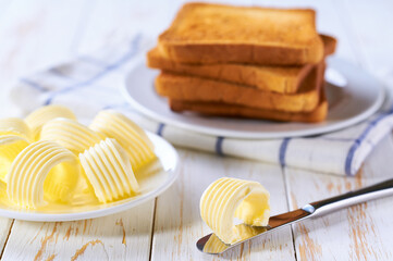 breakfast with butter and toast, in the background you can see a plate with several golden crispy pieces of toast.