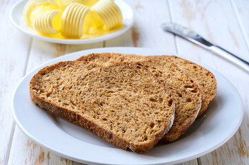 slices rye bread and butter swirls, on a light table selective focus.