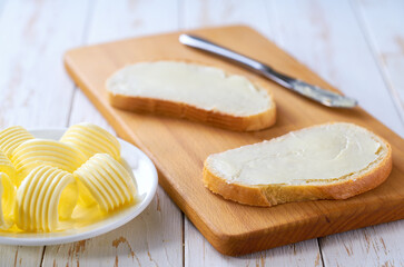 spread butter on a slice of wheat bread on a cutting board, selective focus.