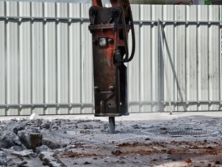 A hydraulic hammer breaking concrete at a construction site