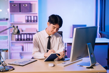 Businessman drinking coffee to get some energy for working overtime sitting at desk using computer and doing overtime