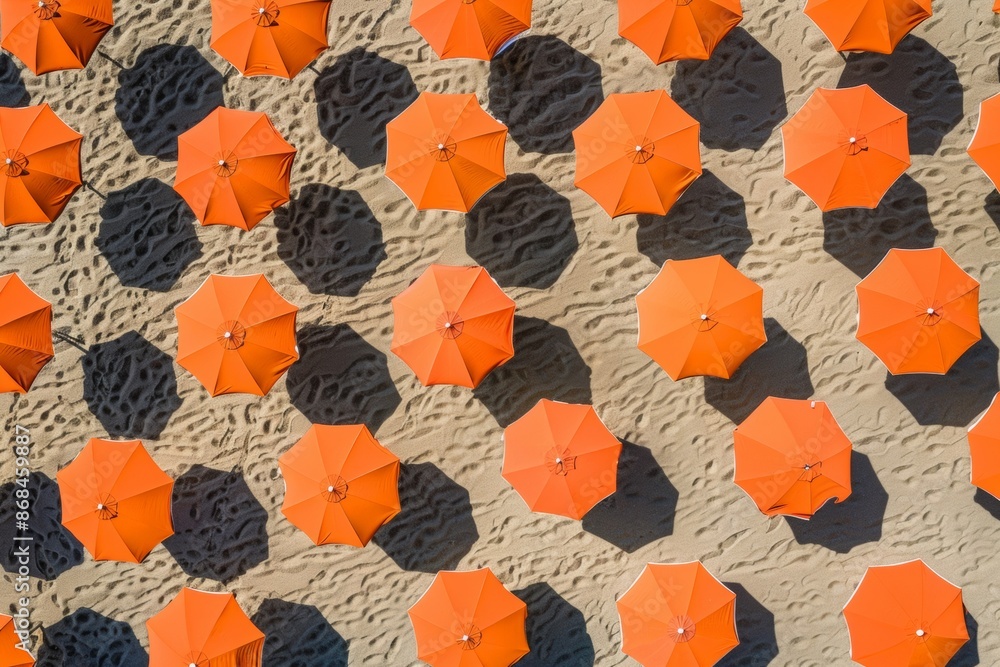 Poster bright sunny day at the beach with symmetrically arranged orange umbrellas casting soft shadows on s
