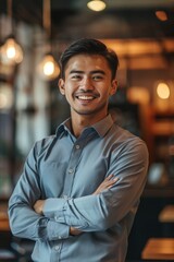 Fototapeta premium A man in a gray shirt is smiling and crossing his arms