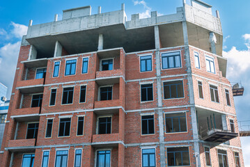 Obraz premium Red brick is used for the construction of exterior walls and partitions in buildings under construction. The frame of the building is made of reinforced concrete. Installation of plastic windows.