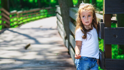 little child girl in summer clothes walking in green park.