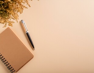 ミモザが飾られたベージュの背景に置かれたノートとペン