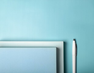 ブルーの背景に重ねて置かれたノートとペン