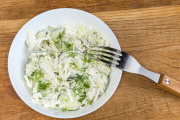 Vegetable salad in bowl with fork on wooden surface