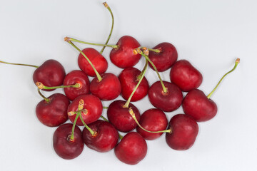 Dark red sweet cherries on stems on a gray background