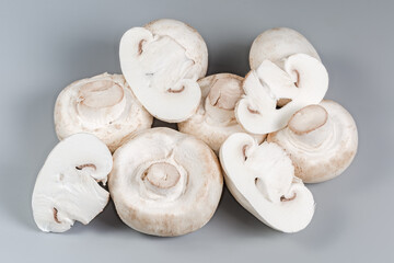 Whole and sliced fresh raw button mushrooms on gray background