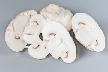 Whole and sliced fresh raw button mushrooms on gray background