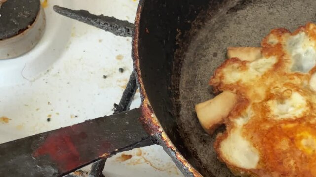 Frying of scrambled eggs with fatback in rustic frying pan