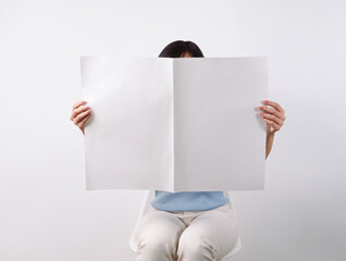Woman reading mockup of blank newspapers to add your own news isolated on white background.