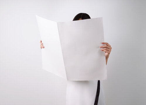 Woman reading mockup of blank newspapers to add your own news isolated on white background.