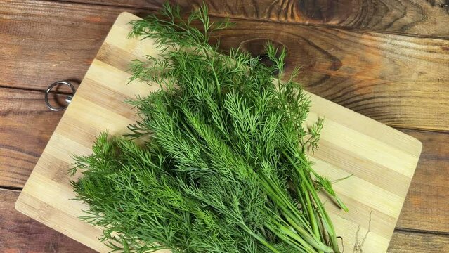 Fresh dill on cutting board on rustic table, top view