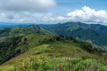 A panoramic summer landscape with snow-capped alpine peaks, green valleys, and fluffy clouds...