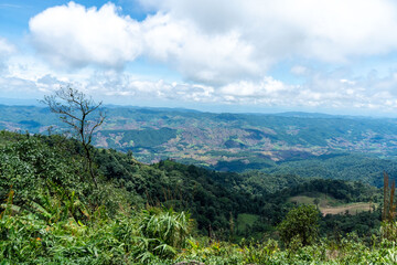 Naklejka premium A scenic summer panorama unfolds, showcasing majestic green mountains capped with clouds against a bright blue sky