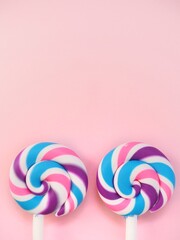 Two colorful lollipops against a pink background. Vibrant candy pops and space to add personalized text
