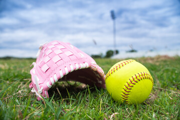 Green softball and pink softball glove on field