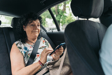 Senior woman sitting in a car using smartphone and exasperating with the trip.Senior woman is using a smartphone while exasperating with her driver in a car.