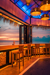 Outdoors beach bar amazing sunset sky. Relaxing beachfront bar with chairs sun umbrellas. Luxury summer travel background. Freedom tropical sunny coast, summertime vibes. Tranquil relaxation
